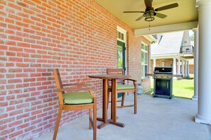A covered patio with a brick wall, a ceiling fan, a table with chairs, and a grill. - Pool Access + Golf View: 5BR Springfield Home (Springfield)