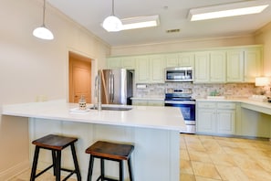 A modern kitchen with a large island, stainless steel appliances, and light green cabinetry.