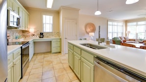A kitchen with green cabinets, a large island with a sink, and a dishwasher. - Pool Access + Golf View: 5BR Springfield Home (Springfield)