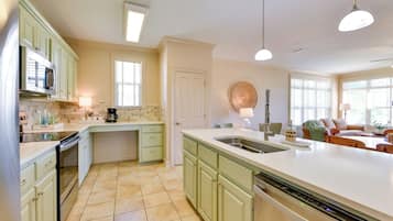 A kitchen with green cabinets, a large island with a sink, and a dishwasher.