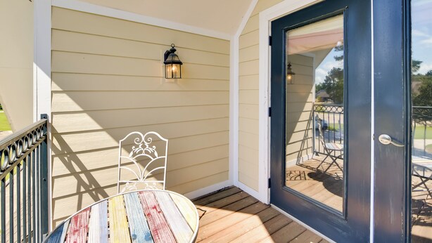A porch with a wooden table and metal chair, a black door, and a small outdoor seating area with a metal railing. - Pool Access + Golf View: 5BR Springfield Home (Springfield)