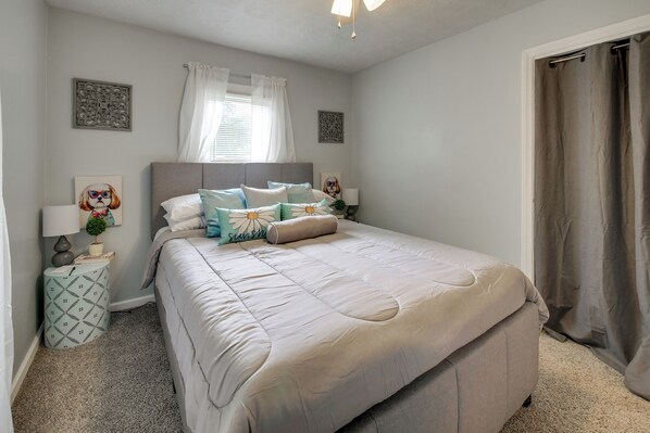 A bedroom with a bed, bedside tables, a window with curtains, and a door.