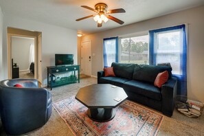 A living room with a sofa, coffee table, and ottoman, a television, and a ceiling fan. - 1 Mi to Fort Valley State College! Home w/ Grill (Fort Valley)