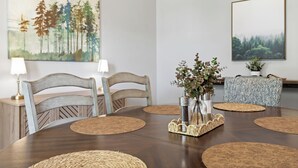 En matplats med ett träbord, två stolar, en vas med blommor och två vägglampor.