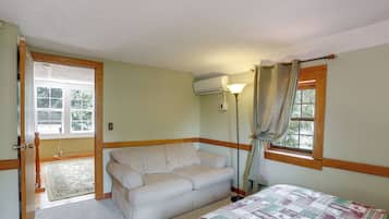 A room with a bed, a sofa, a lamp, and a window with curtains.