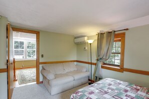 A room with a bed, a sofa, a lamp, and a window with curtains.