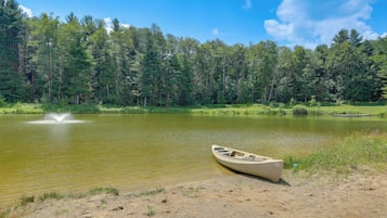 A calm lake with a canoe on the shore, surrounded by dense forest.