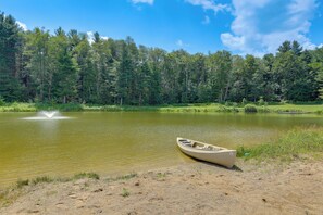A calm lake with a canoe on the shore, surrounded by dense forest.