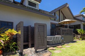 Ein Haus mit Terrasse, Whirlpool und überdachter Bereich mit Sonnenschirm.