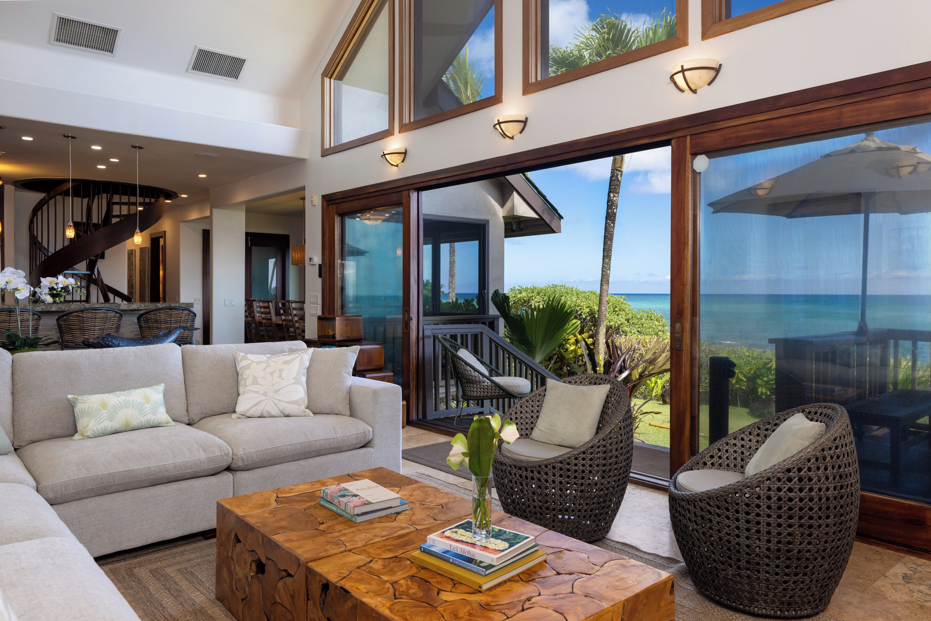 A modern living room with a sofa, chairs, a coffee table, and a view of the ocean.