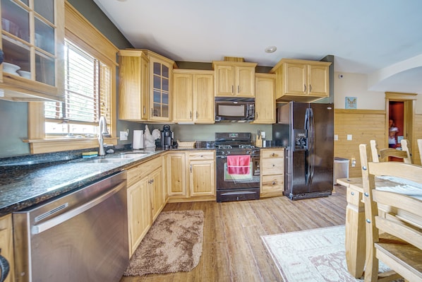 A kitchen with wooden cabinets, a stainless steel refrigerator, a microwave, and an oven.