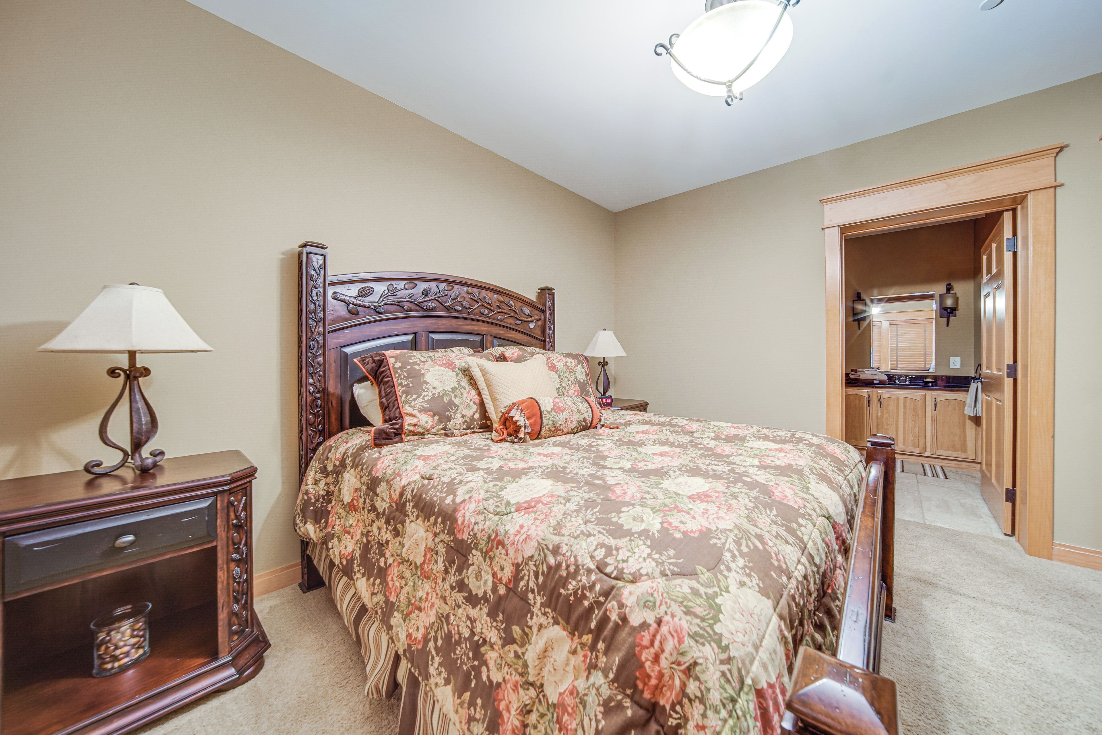 A bedroom with a wooden bed, two bedside tables, a nightstand, a closet, and a hallway.