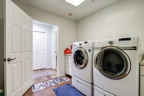 A laundry room with two front-loading washers and dryers, a white door, and a doormat.