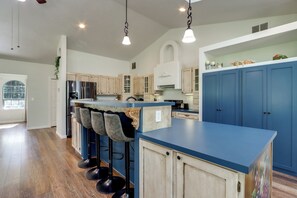 Eine moderne Küche mit blauer Arbeitsplatte, Barhocker und einem eingebauten Backofen.
