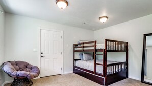 A room with a bunk bed, a chair, and a door. - Riffle Road Ranch: 10 Acres, 8 Mi to Silverwood (Spirit Lake)