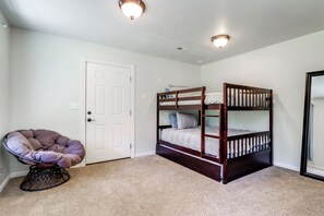 Ein Zimmer mit einem Etagenbett, einem Sessel und einer Tür.