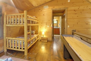 A wooden cabin interior with bunk beds, a small table with a lamp, and a shuffleboard table. - Blue Ridge Bliss: Peaceful Retreat w/ Deck (Blue Ridge)