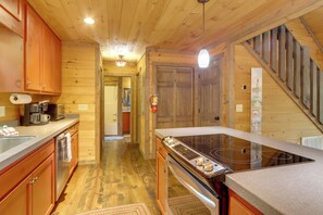 A wooden cabin interior with a kitchen area featuring a stove, cabinets, and a wooden staircase. - Blue Ridge Bliss: Peaceful Retreat w/ Deck (Blue Ridge)