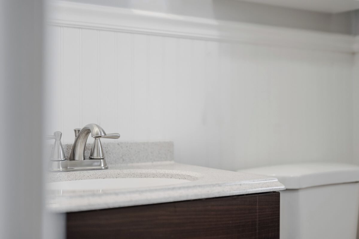 A bathroom with a white sink, a faucet, and a mirror.