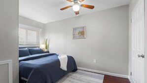 A bedroom with a bed, a ceiling fan, a window with blinds, a painting on the wall, and a door. - Mt Washington Retreat w Dedicated Parking Pets OK (Pittsburgh)