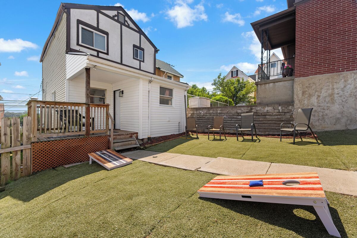 A backyard with a wooden deck, a trampoline, and a patio area with chairs.