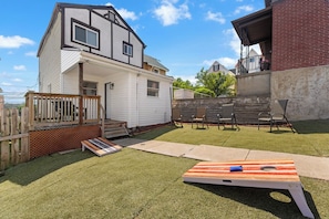 Ein Garten mit einer Holzterrasse, einem Trampolin und einer Terrasse mit Sitzgelegenheiten.