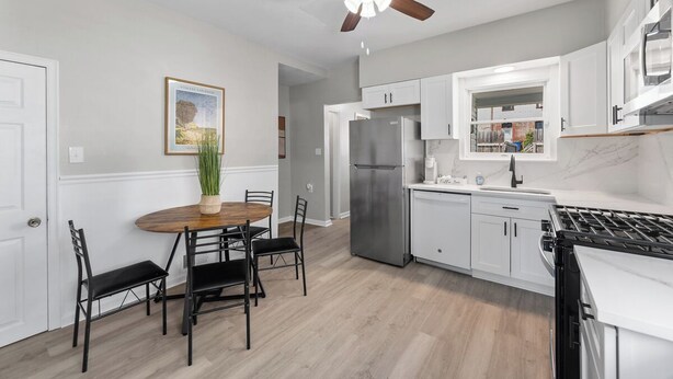 A modern kitchen with white cabinets, a stainless steel refrigerator, a gas stove, and a ceiling fan. - Mt Washington Retreat w Dedicated Parking Pets OK (Pittsburgh)
