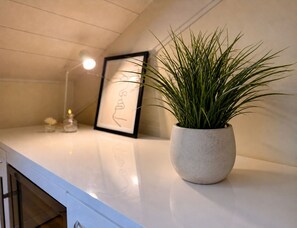A potted plant on a white countertop with a framed picture and a small candle. - Ponte degli Alpini | Luxury Penthouse · Sauna, 2 Hot Tubs & Panoramic Terrace (Bassano del Grappa)
