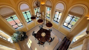 Ein Zimmer mit hohen Decken, einem runden Tisch in der Mitte, mehreren Stühlen und einer Kristallleuchter.