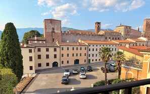 A parking lot with several cars, a building with a tower, and a castle-like structure in the background. - Ponte degli Alpini | Luxury Penthouse · Sauna, 2 Hot Tubs & Panoramic Terrace (Bassano del Grappa)
