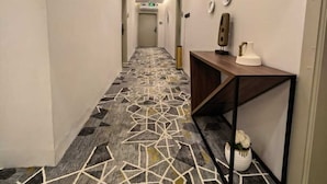 Ein Hotelgang mit einem geometrisch gemusterten Teppich, einem Empfangstresen und einem an der Wand befestigten Schild.