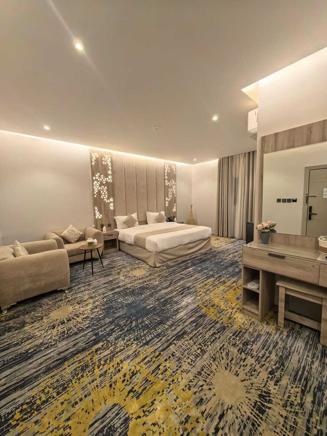 A modern hotel room with a bed, sofa, and a small table.