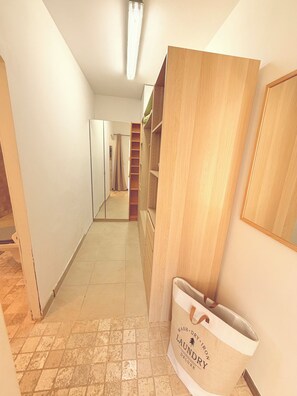 A hallway with a wooden wardrobe, a white bag with text, and a tiled floor. - Large villa with a large pool and a gym (Grasse)