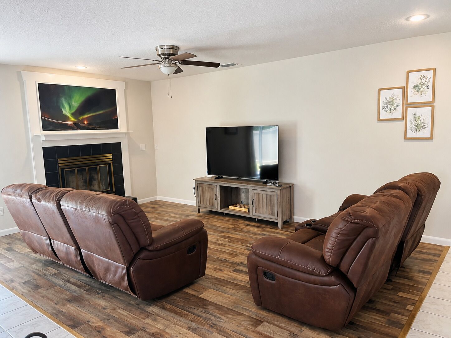 A living room with two leather recliners, a flat-screen TV, a fireplace, and a ceiling fan.