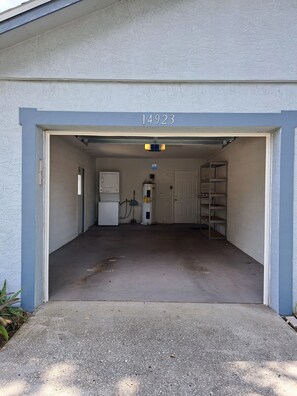 A garage with a white door, a water heater, and a gas pump. - Cozy Tampa Home (Tampa)