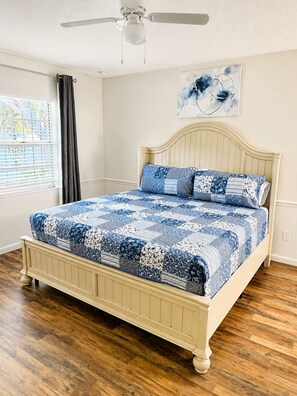 A bedroom with a bed, a ceiling fan, a window with blinds, and a wall-mounted artwork. - Cozy Tampa Home (Tampa)