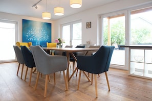 Un comedor moderno con una mesa de madera, seis sillas e iluminación colgante.
