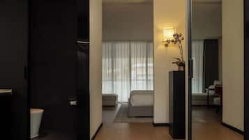 Ein modernes Hotelzimmer mit Holzboden, einer Couch, einem kleinen Tisch und einer Topfpflanze.