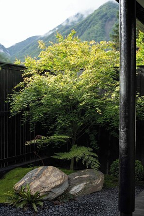 Un jardin avec un arbre, des rochers et une clôture en bois.