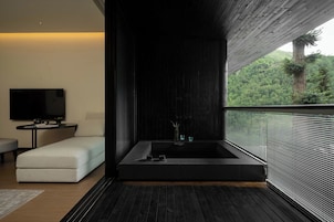 Un baño moderno con una bañera grande, un televisor de pantalla plana y vistas a un bosque.