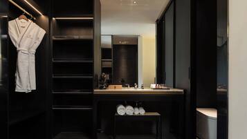 A modern bathroom with a dark wood vanity, a large mirror, and a robe hanging on a rack.