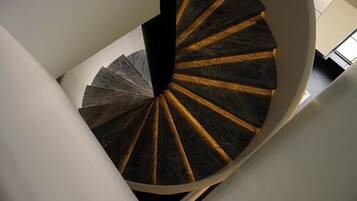 A spiral staircase with a dark, patterned floor and white walls.