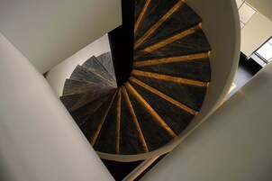 A spiral staircase with a dark, patterned floor and white walls.