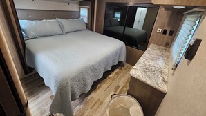 Een kleine slaapkamer met een bed, een wastafel en een spiegel.