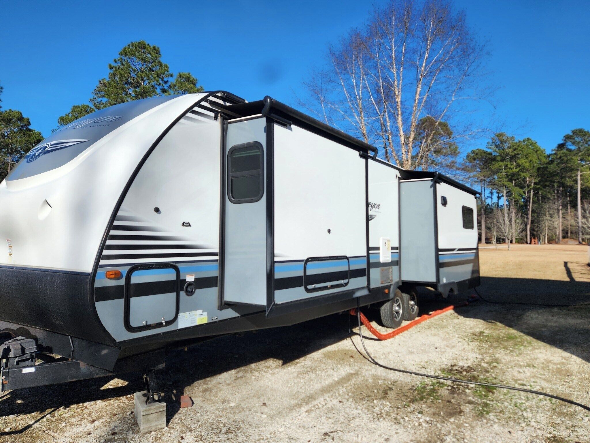 Een witte camper met een schuifdeur, een klein raam en een blauwe streep.