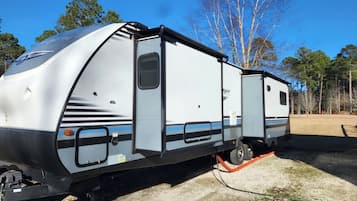 Een witte camper met een schuifdeur, een klein raam en een blauwe streep.