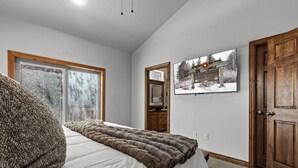 Ein Schlafzimmer mit einem Bett, einem Fenster, einer Tür und einem an der Wand hängenden Bild.