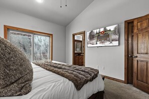 A bedroom with a bed, a window, a door, and a wall-mounted picture. - Corner Home-Private Garage-Clubhouse | Sleeps 12 | Moose Mgmt 5672 (Park City)