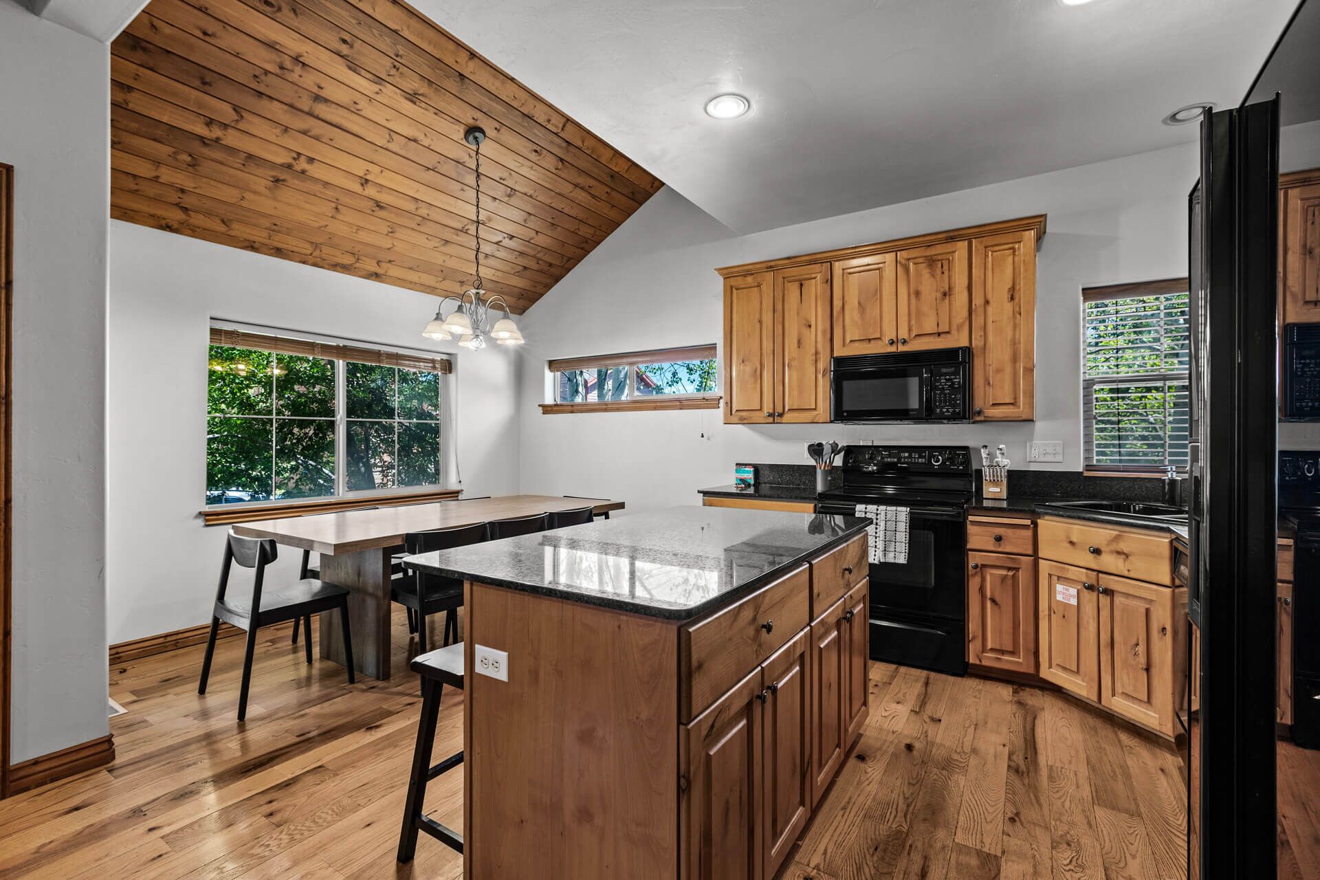 A modern kitchen with wooden cabinets, a central island, and a large window providing natural light.