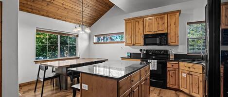 A modern kitchen with wooden cabinets, a central island, and a large window providing natural light.